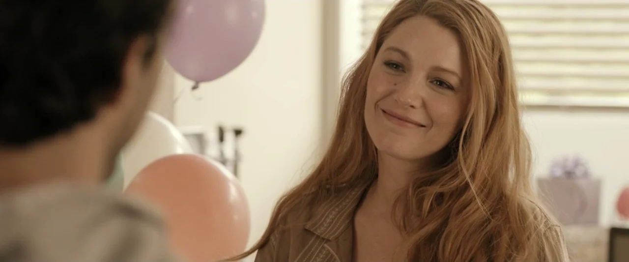 It Ends with Us (2024) movie still: medium — A bright indoor room decorated with pastel balloons for a celebration. A smiling woman looks at a man…