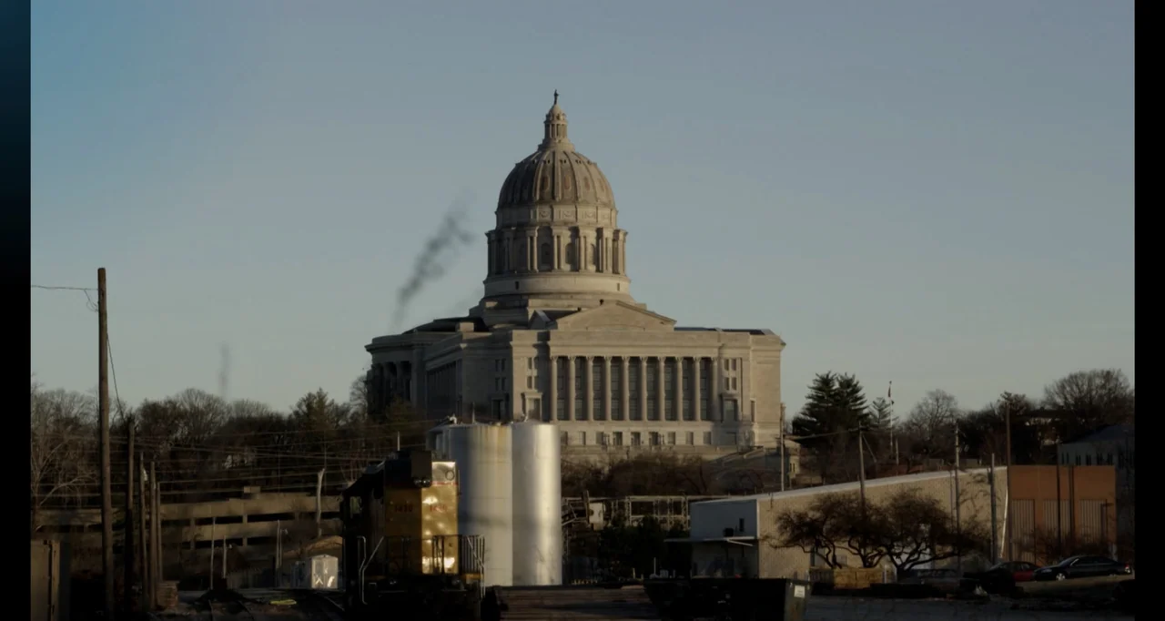 Abortion: Stories Women Tell (2016) movie still: wide — A large stone domed capitol building sits prominently on a hill in the distance. A train…