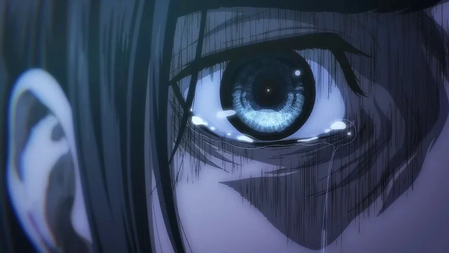 Attack on Titan (2013) movie still: closeup — An extreme close-up focuses on a single human eye framed by dark, vertical shading. A tear forms on…