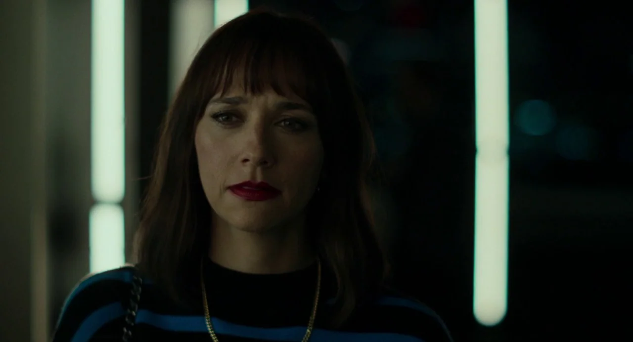 On The Rocks (2020) movie still: closeup — A dimly lit indoor corridor features vertical glowing light fixtures on the dark walls. A woman with dark…