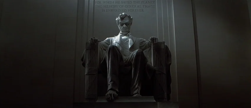 Planet of the Apes (2001) movie still: fullbody — A stone monument features a large chair occupied by a seated simian figure. Inscribed lettering on…