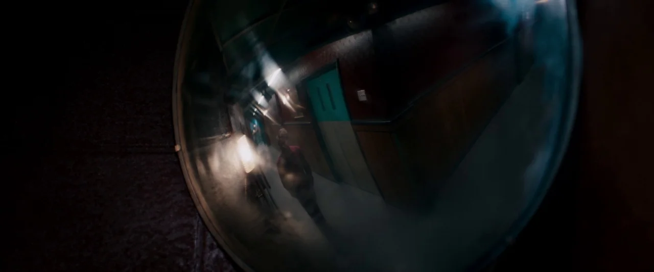 The Autopsy of Jane Doe (2016) movie still: closeup — A long hallway with dark red walls and teal doors is filled with light haze. A single man…