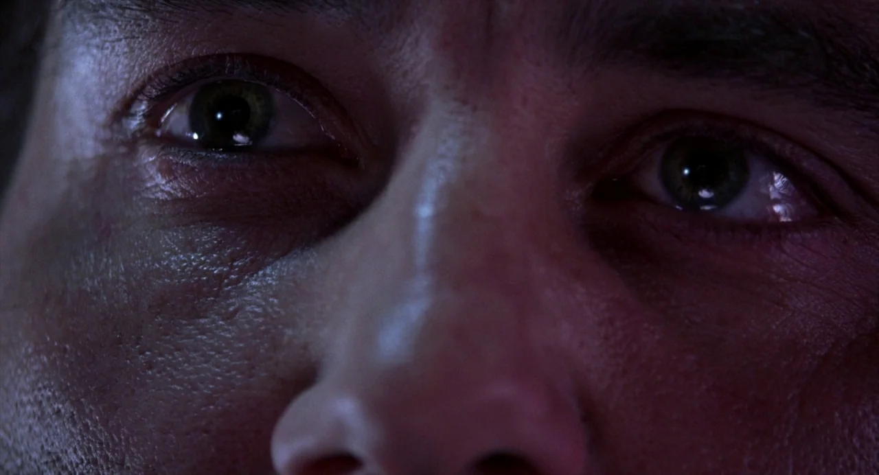 Closer (2004) movie still: closeup — Extreme close-up of a human face in a dark, dimly lit environment. A person stares forward with visible…
