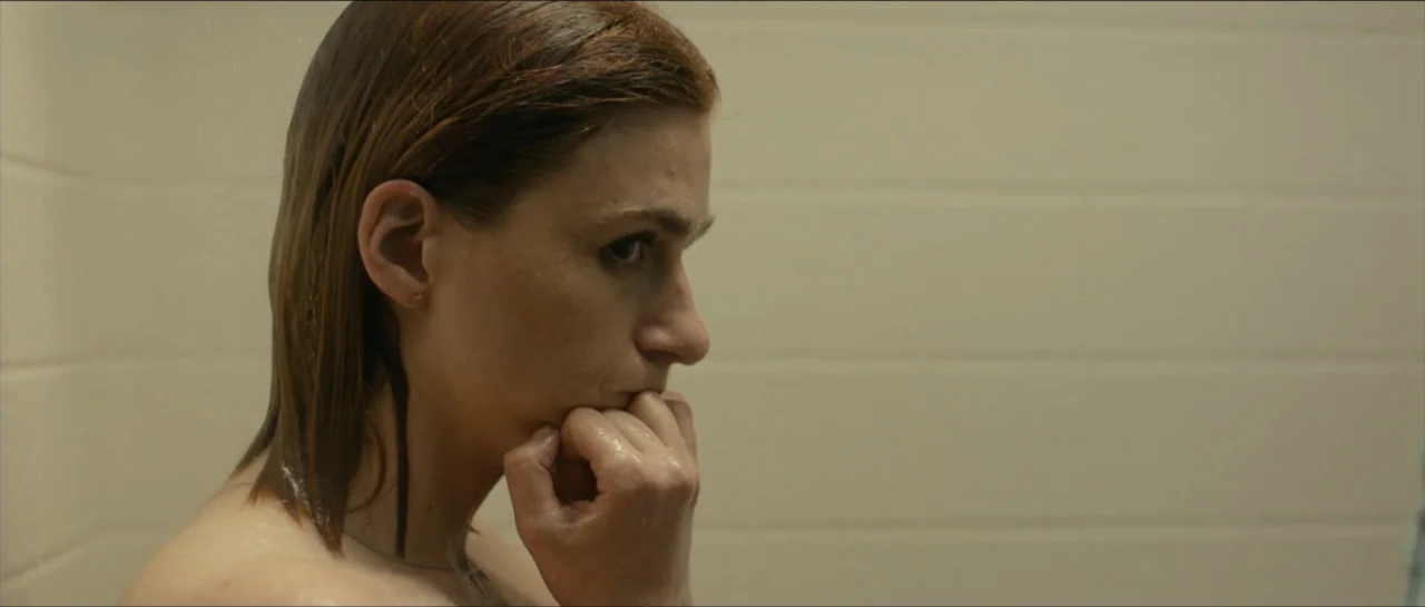 We Broke Up (2021) movie still: closeup — A tiled shower interior with beige wall panels and water droplets visible. A woman with wet hair stands in…