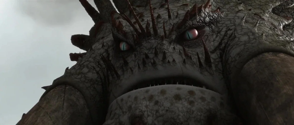 How to Train Your Dragon 2 (2014) movie still: closeup — A massive creature looms over the camera against a flat, cloudy sky. The creature has…