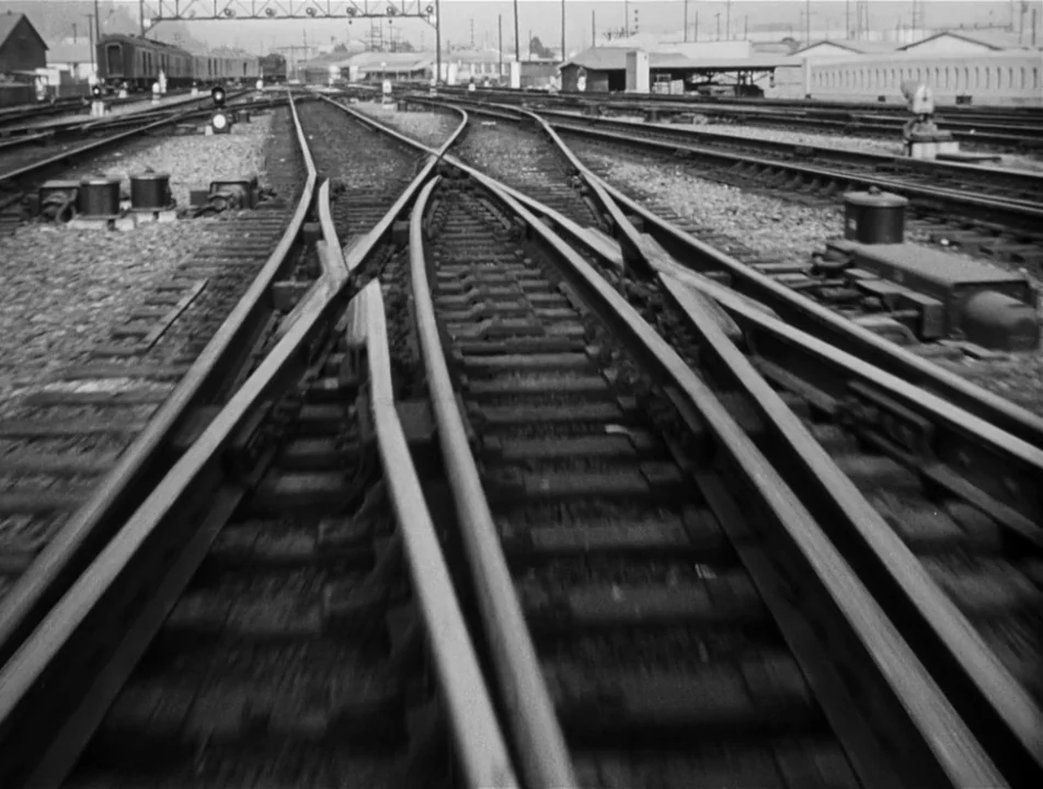 Strangers on a Train (1951) movie still: establishing — A complex network of converging railroad tracks stretches toward a distant industrial yard.…