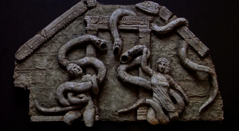 Freddy’s Dead: The Final Nightmare (1991) movie still: closeup — A stone bas-relief depicts two human figures entwined with multiple snakes near…