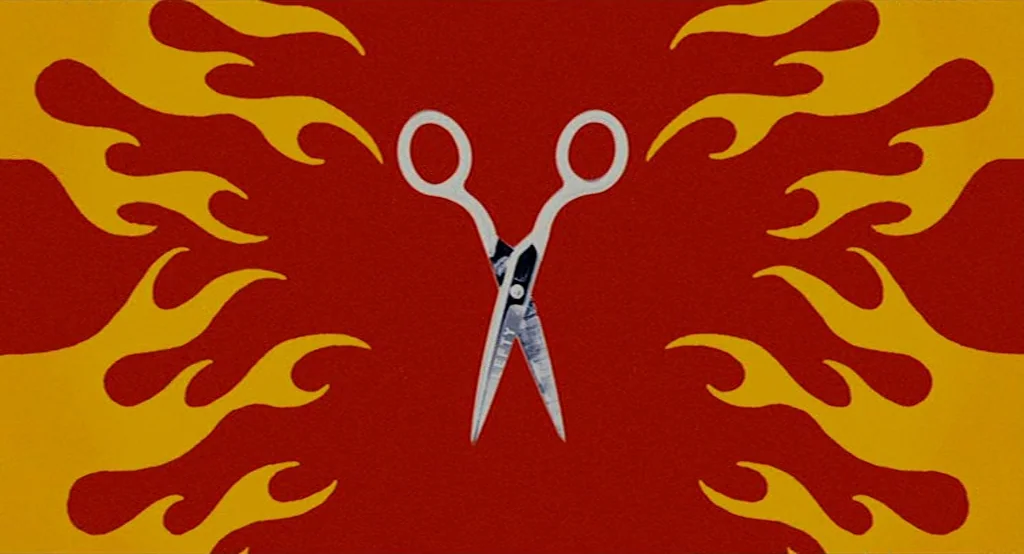 Moonrise Kingdom (2012) movie still: closeup — A flat graphic design features a central pair of silver scissors. Stylized yellow flame motifs…