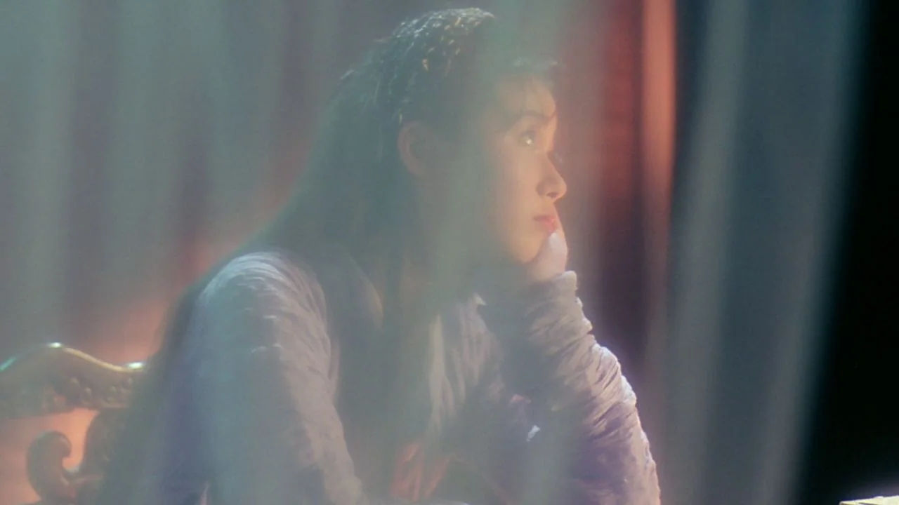 The Bride with White Hair II (1993) movie still: A pensive young woman is captured in a soft-focused, dreamlike medium close-up, lit by a warm, hazy…