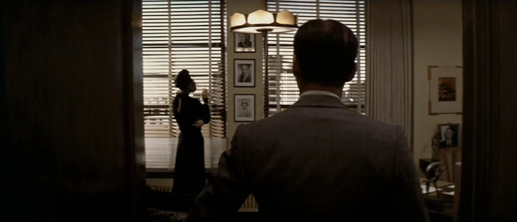 Chinatown (1974) movie still: medium — An interior space features wood-paneled walls and a window covered with horizontal Venetian blinds. A man in…
