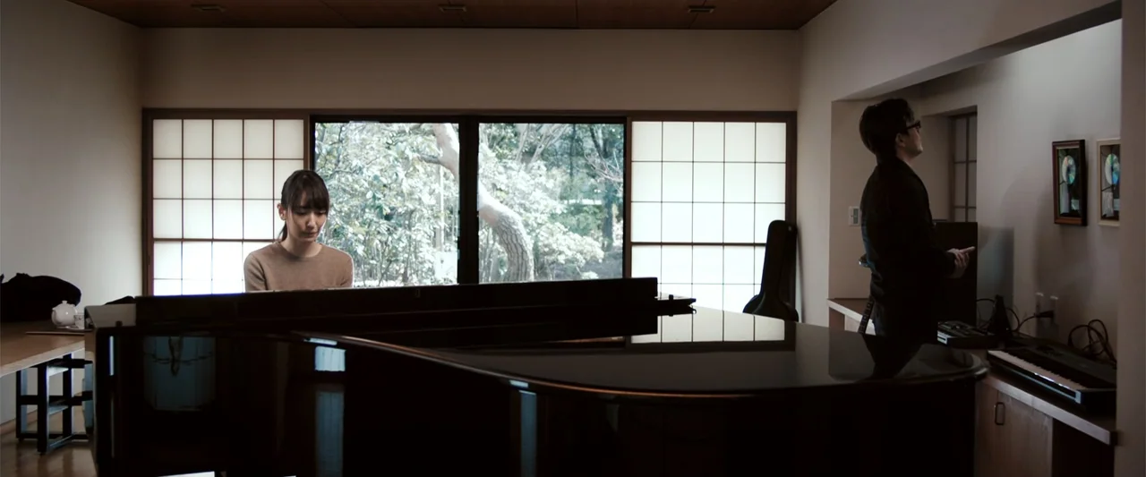 To Hear the Birds Singing (1995) movie still: wide — A room with large paper-paneled sliding windows looking out onto a treed exterior. A woman…