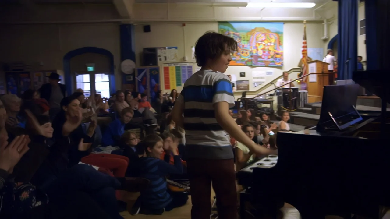 Moonlight Sonata: Deafness in Three Movements (2019) movie still: medium — An audience sits in a school auditorium decorated with colorful student…