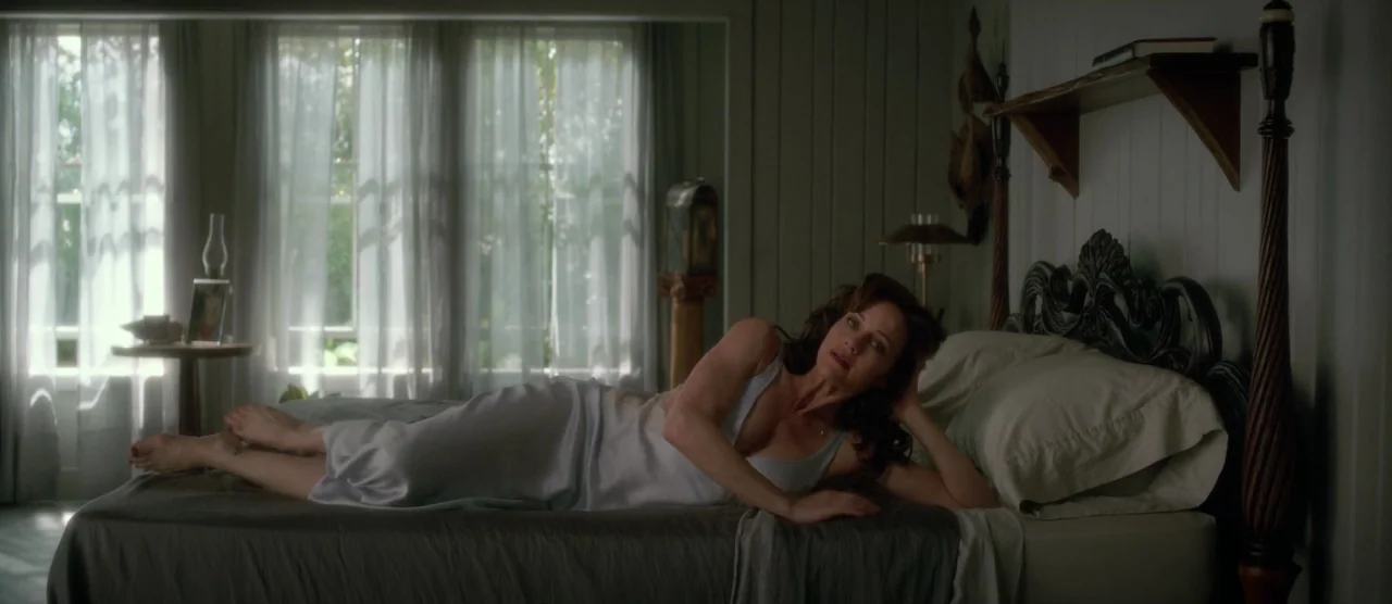 Gerald’s Game (2017) movie still: fullbody — A room with white paneled walls and sheer curtains covering large windows. A woman wearing a silk gown…