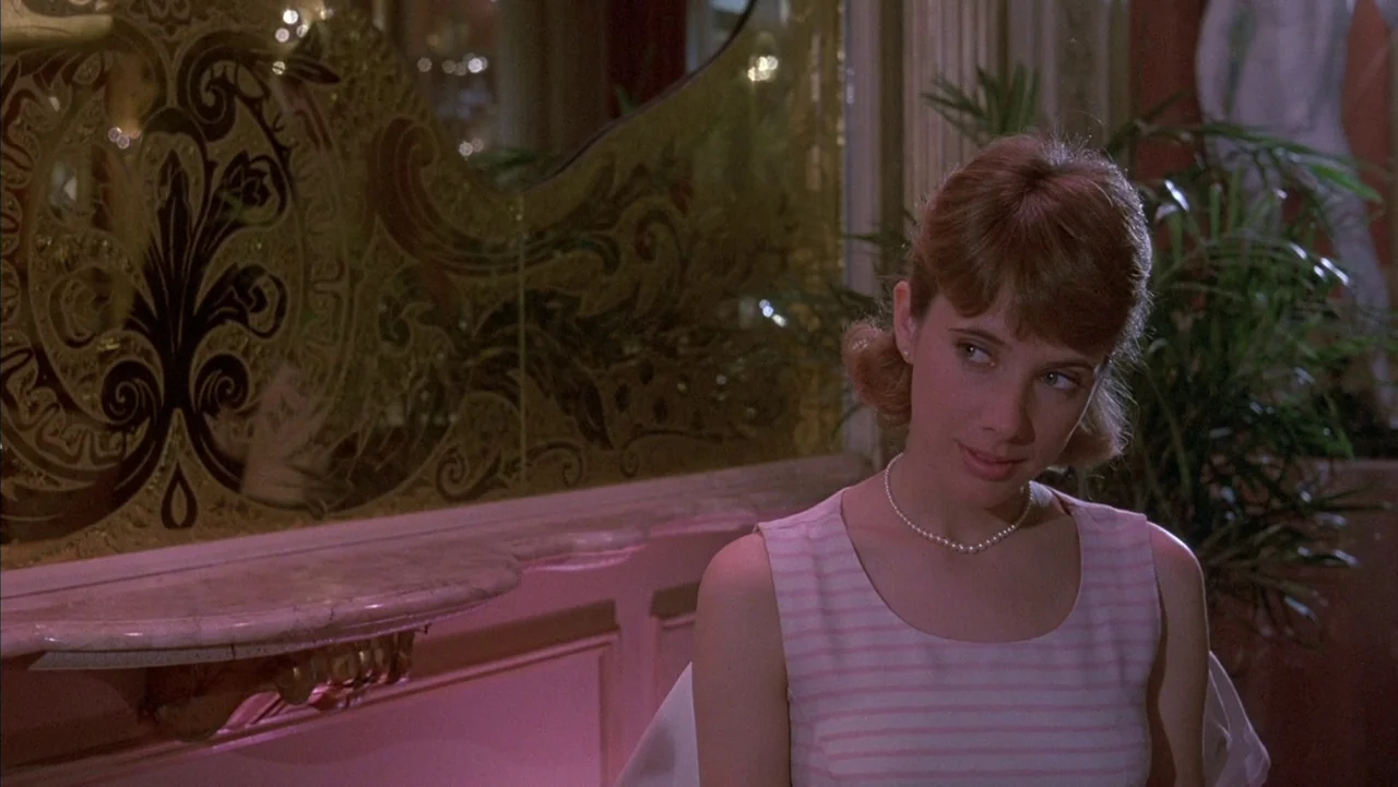 Baby It’s You (1983) movie still: medium — A refined interior space features a pink-painted wall adorned with an ornate gold-framed mirror. A young…