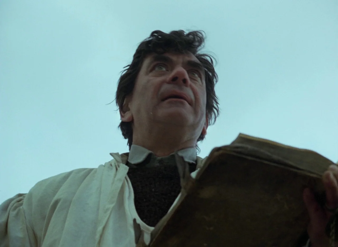 Faust (1994) movie still: medium — A man stands outdoors under an overcast sky holding an open, worn book. He looks up towards the sky with his…