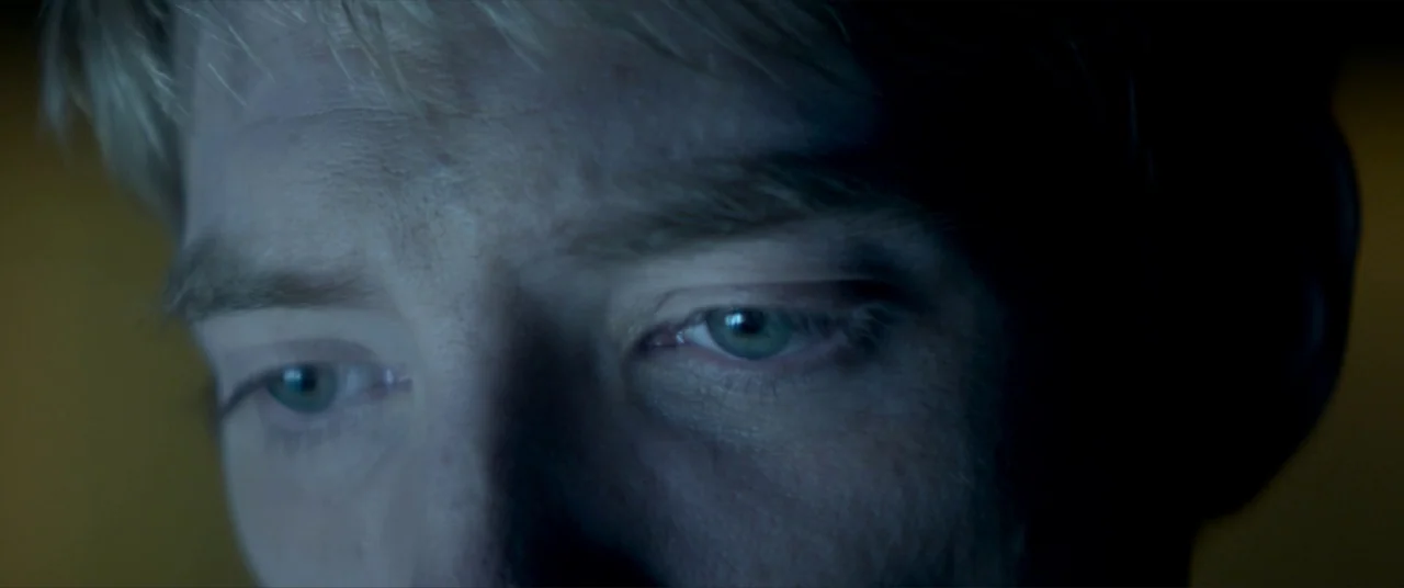 Ex Machina (2015) movie still: closeup — A dimly lit room provides the backdrop for a tight facial close-up. The person's eyes are illuminated by a…