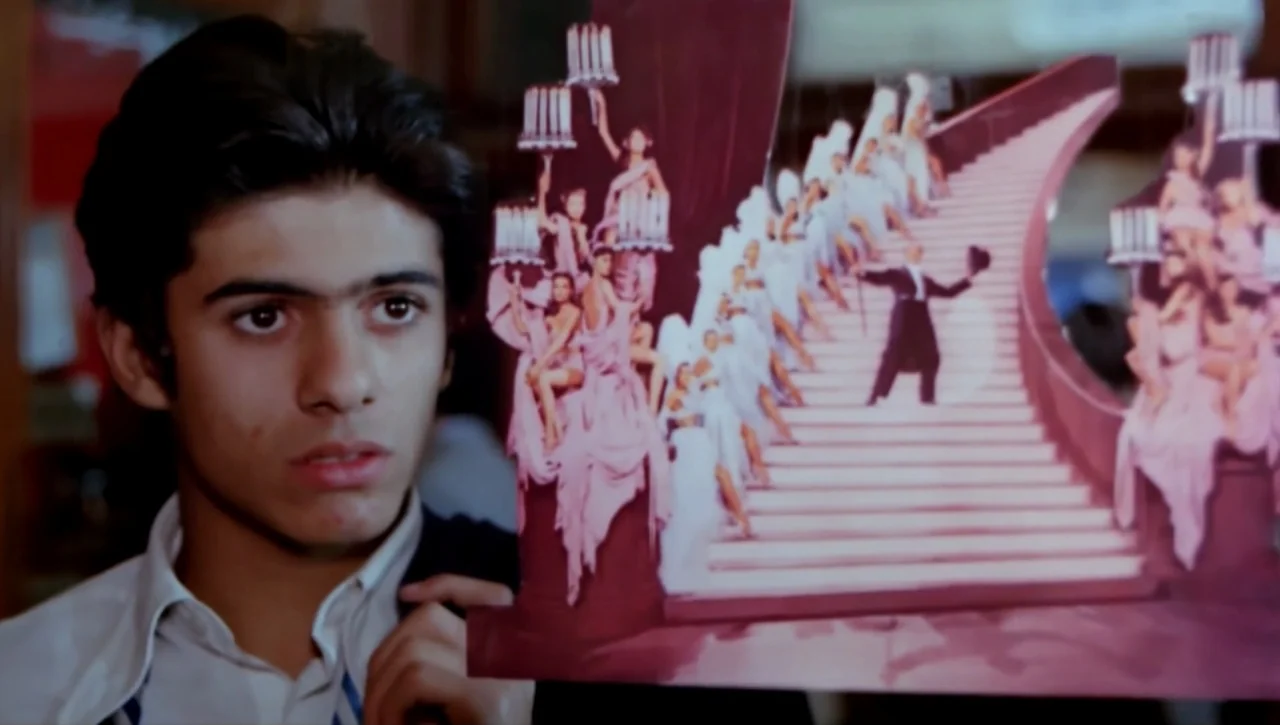 Alexandria…Why? (1979) movie still: closeup — A teenage boy holds a theatrical promotional card in an interior space. The card displays a stage…