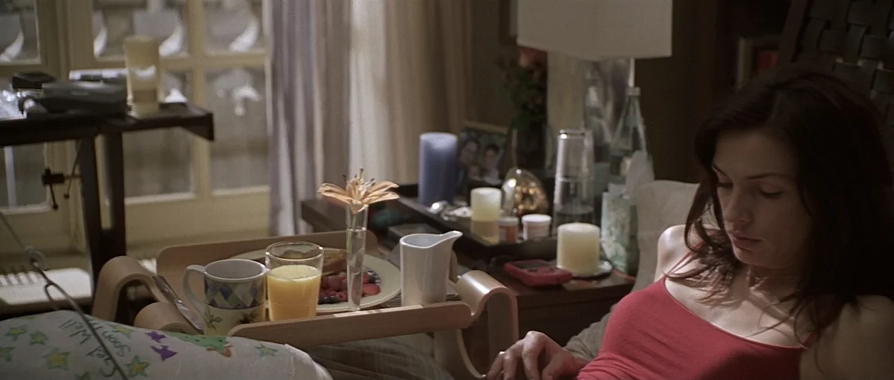 Don't Say a Word (2001) movie still: medium — A bedroom contains a breakfast tray on a wooden lap desk over the bed. A young woman in a red tank top…