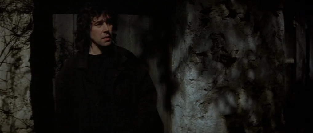 The Crying Game (1992) movie still: medium — A man stands before a rough stone wall at night. Deep shadows fall across the scene.