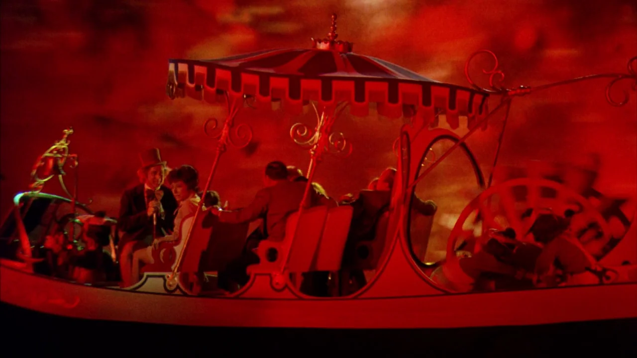 Willy Wonka & the Chocolate Factory (1971) movie still: wide — A boat with an ornate striped canopy floats through a dark, red-lit space. Several…