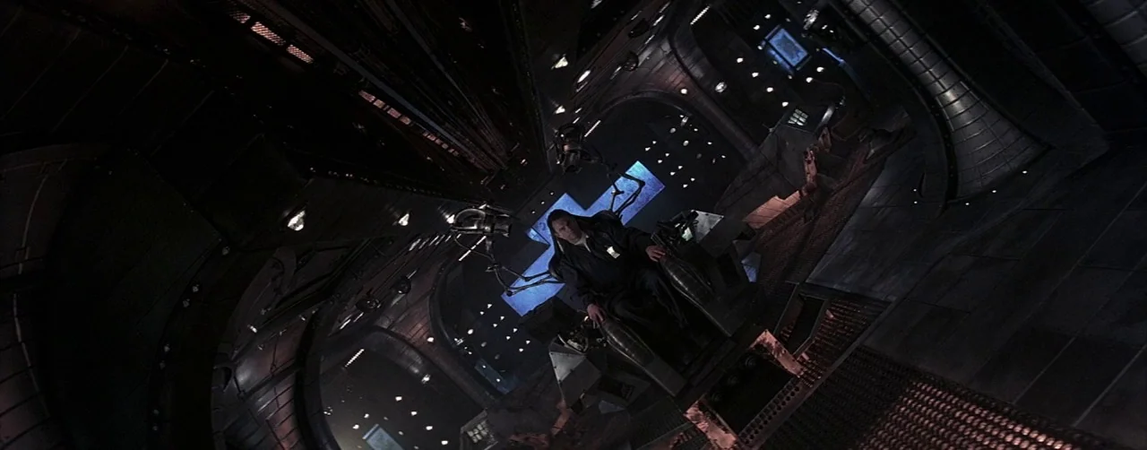 Event Horizon (1997) movie still: wide — A dark, metallic futuristic cockpit interior featuring curved walls and complex control panels. A man sits…
