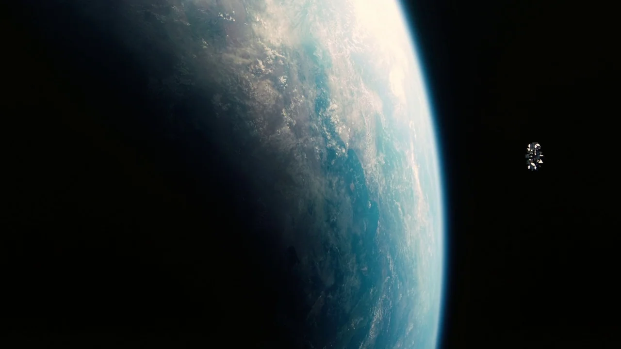 Interstellar (2014) movie still: establishing — A vast view of a curved planet edge seen from deep space. A tiny spacecraft floats against the dark…