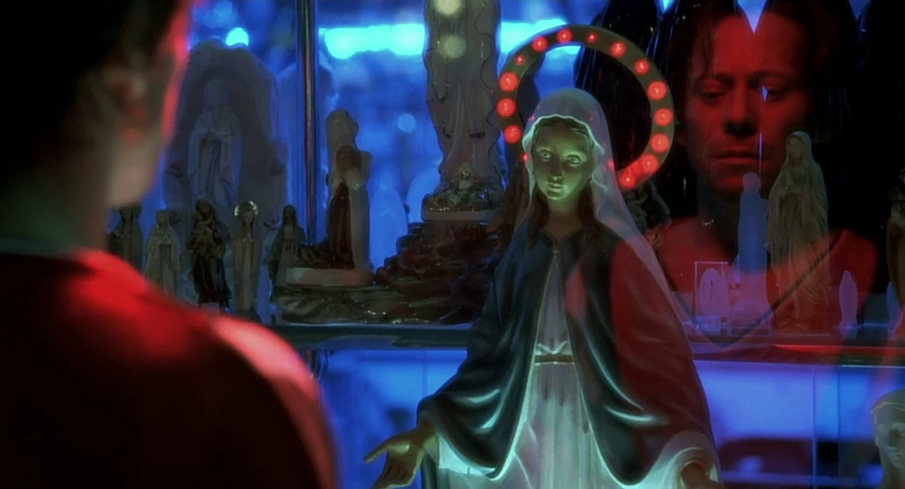 The Diving Bell and the Butterfly (2007) movie still: medium — A glass display shelf contains numerous plastic religious figurines of the Virgin…