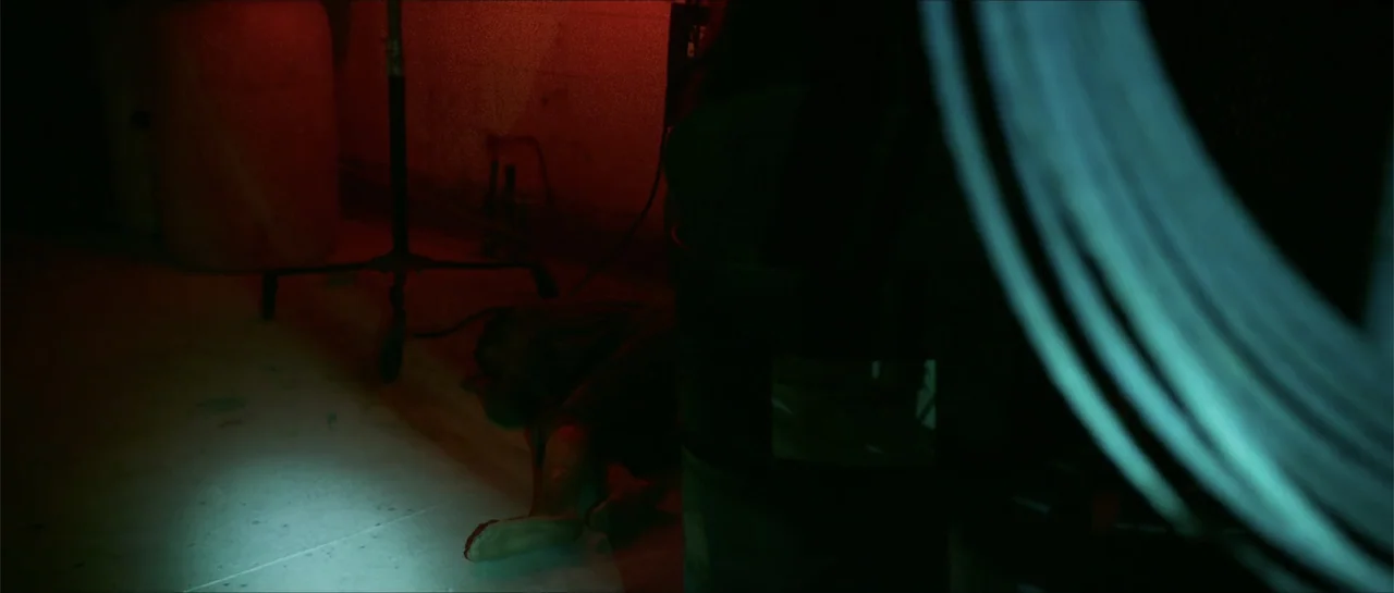 The Vault (2017) movie still: wide — A dark, industrial concrete basement space contains various production equipment and tangled black cables. A…
