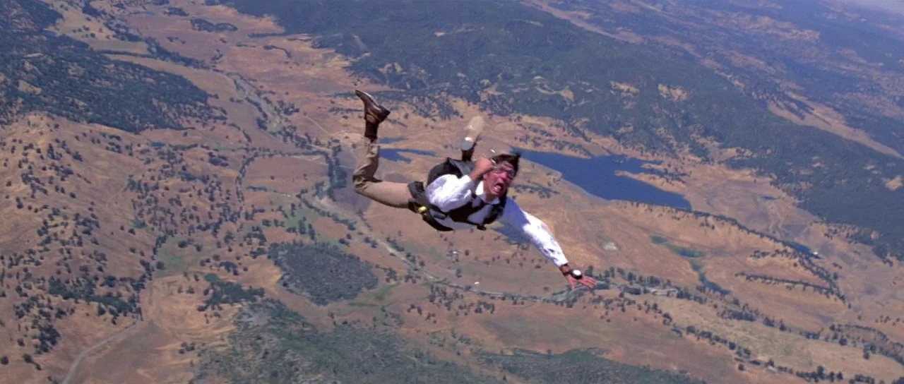 Moonraker (1979) movie still: wide — An aerial view shows a person falling over a large expanse of rolling dry landscape. The individual is…