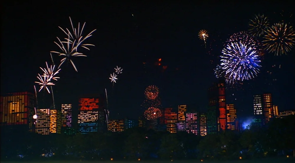 The Fisher King (1991) movie still: establishing — A dark night skyline shows numerous high-rise buildings with scattered glowing office windows.…