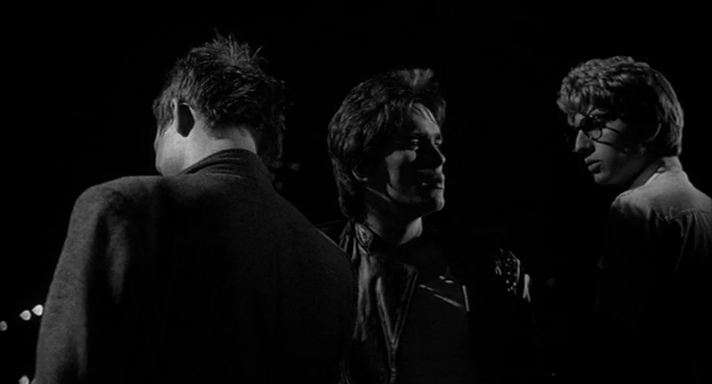 Rumble Fish (1983) movie still: medium — Three young men stand in the darkness of a nighttime city street. They are positioned close together with…