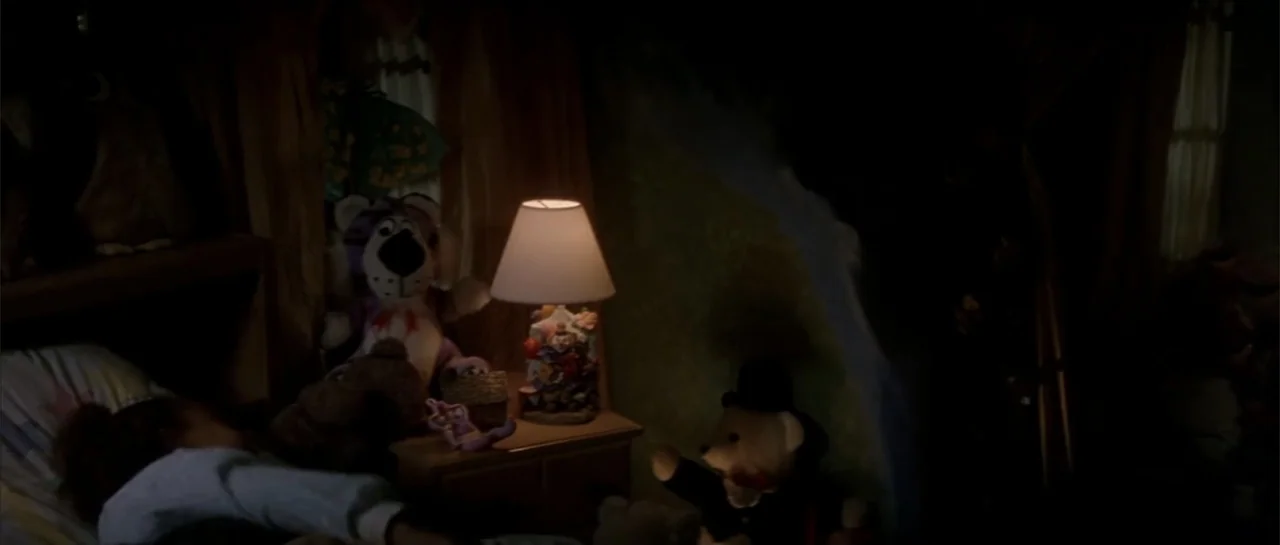 Moonlight and Valentino (1995) movie still: medium — A dimly lit bedroom features a child sleeping in a bed covered in stuffed animals. A bedside…