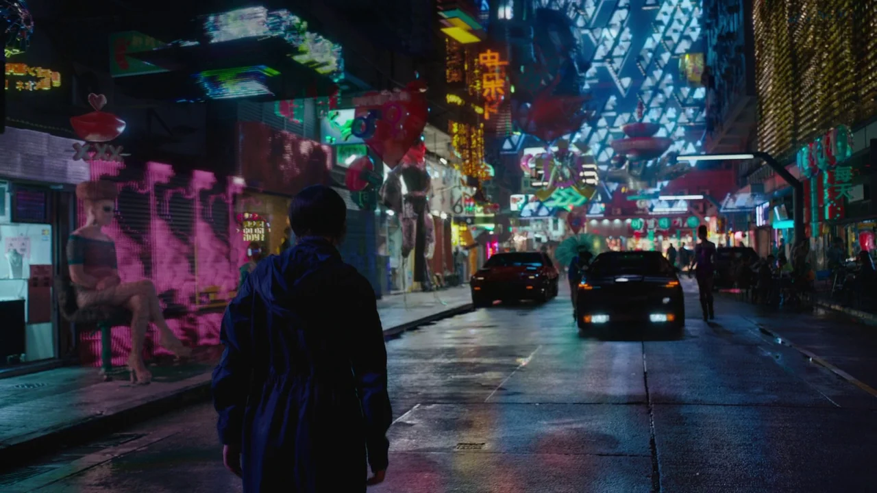 Ghost in the Shell (2017) movie still: fullbody — A dense futuristic city street at night is crowded with hanging neon advertisements and signage. A…