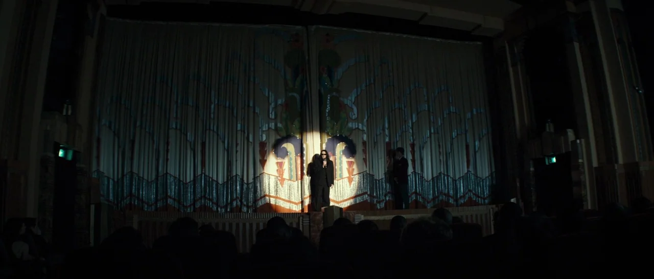 The Disaster Artist (2017) movie still: wide — An ornate Art Deco theater auditorium features a large, intricately designed stage curtain. Two men…