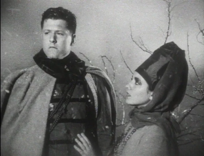 Archangel (1990) movie still: medium — A man and a woman stand together against a backdrop of bare tree branches. Falling snow is visible against…