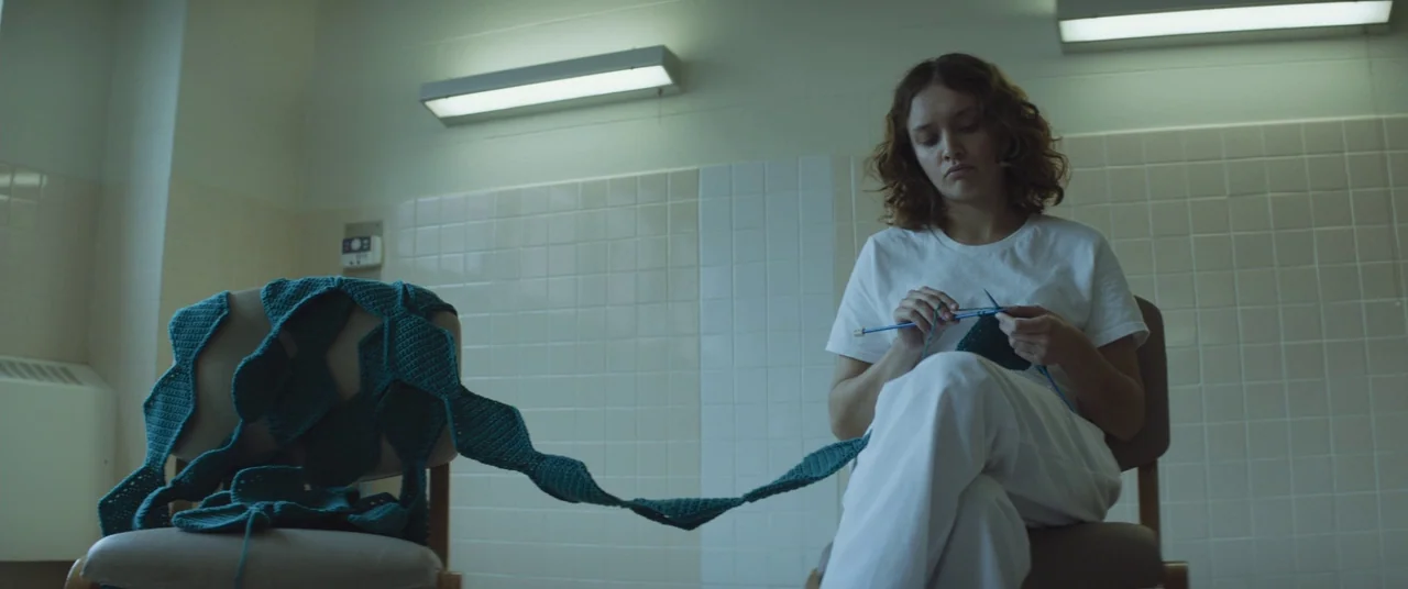 Thoroughbreds (2017) movie still: medium — A stark room with pale white tiled walls and overhead strip lighting. A young woman sits on a chair,…