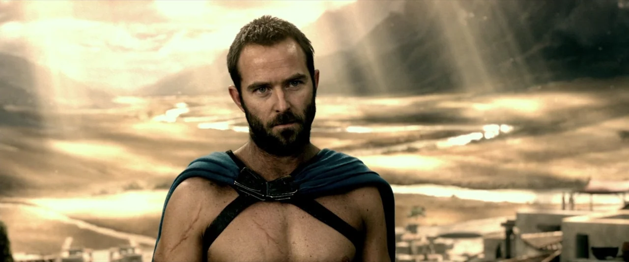 300: Rise of an Empire (2014) movie still: medium — A vast, arid valley stretches out under a bright, cloud-filled sky. A muscular man in a blue…