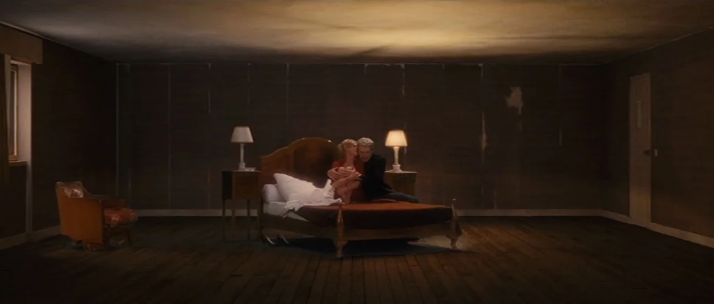 You Ain’t Seen Nothin’ Yet (2012) movie still: wide — A sparsely furnished room with dark wood walls and a large, central wooden bed. A man and a…