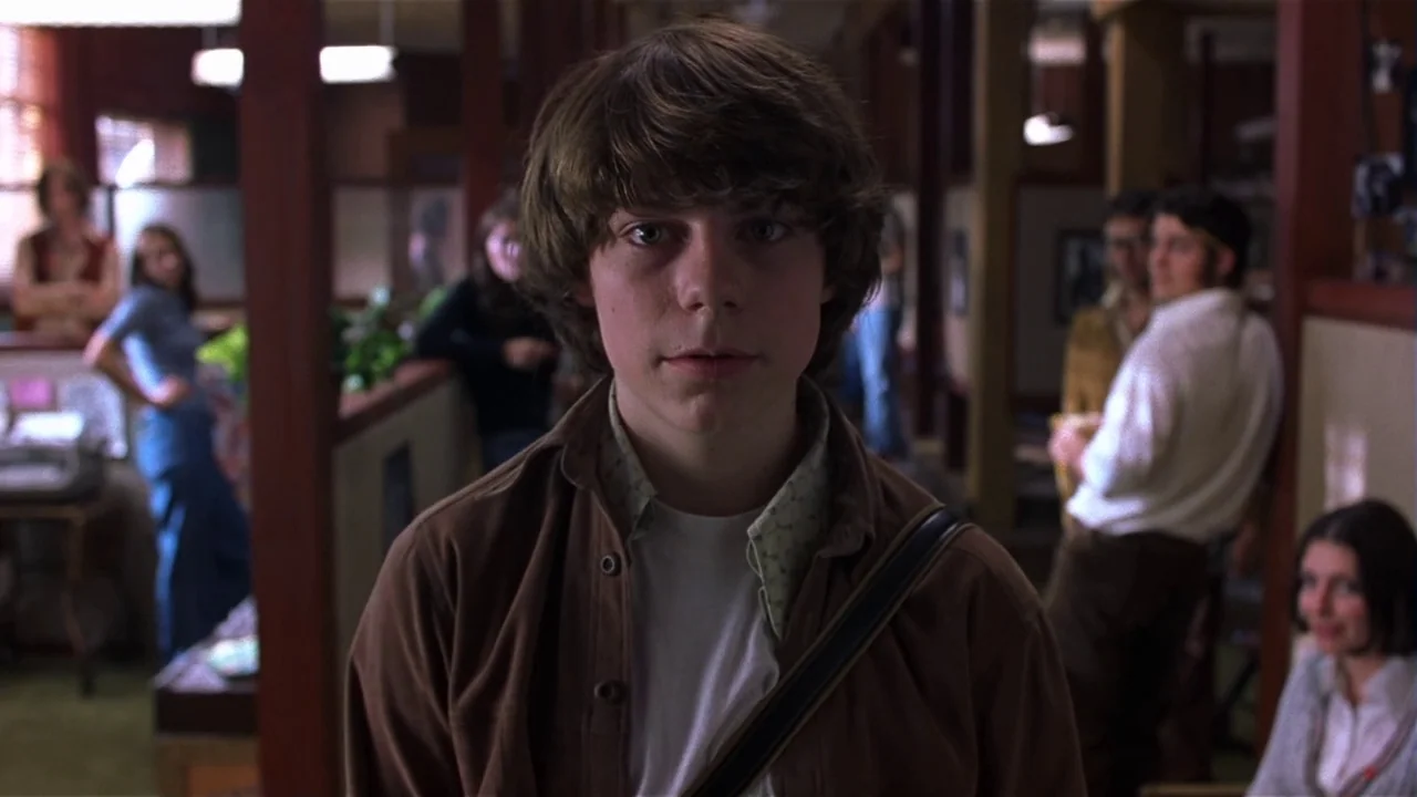Almost Famous (2000) movie still: medium — An open-plan workspace features partitions and several people working in the background. A young male…