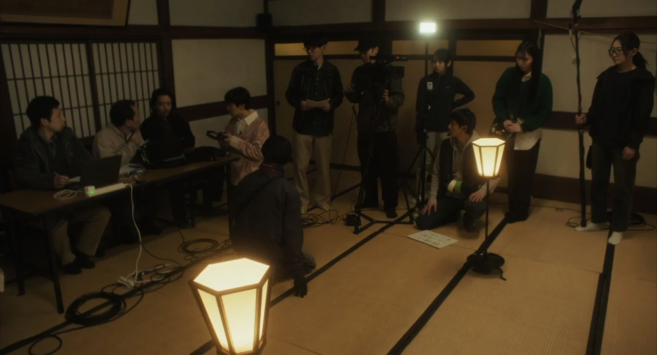 Stigmatized Properties: Possession (2025) movie still: wide — A group of people assemble filming equipment in a Japanese-style room with tatami…