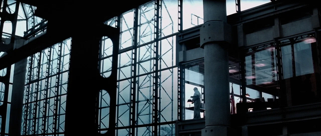 Spy Game (2001) movie still: wide — A modern building interior features vast floor-to-ceiling windows supported by heavy black metal girders. A…