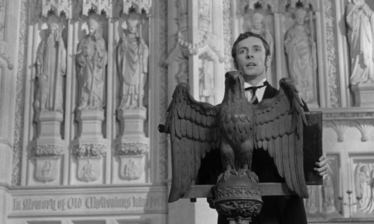 If…. (1968) movie still: medium — A man stands behind an ornate wooden eagle lectern inside a stone church sanctuary. The background features…