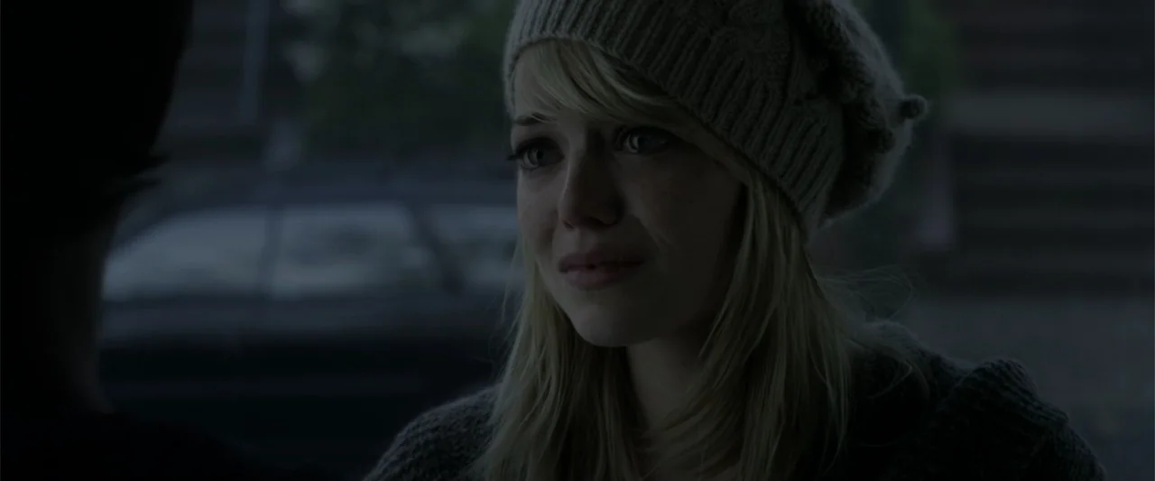 The Amazing Spider-Man (2012) movie still: closeup — An exterior street scene at dusk features a young woman in a beanie.