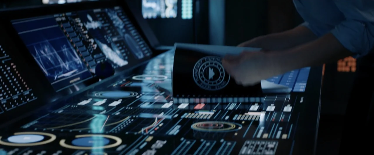 2036 Origin Unknown (2018) movie still: medium — A dimly lit room features a large digital console illuminated by vibrant interface graphics. A…