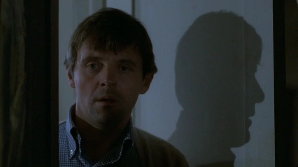 Magic (1978) movie still: closeup — A man stands in a doorway looking into a darkened adjacent room. His shadow is projected clearly onto the white…