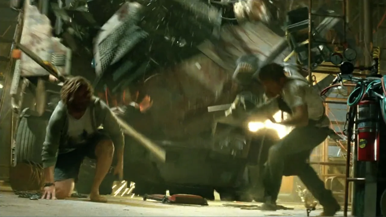 Transformers: Age of Extinction (2014) movie still: medium — A cluttered garage filled with metal debris and mechanical tools undergoes a violent…