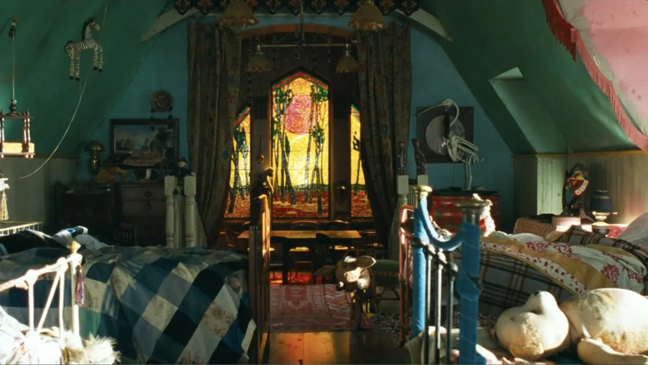 Nanny McPhee and the Big Bang (2010) movie still: wide — An attic bedroom features teal walls, patterned quilts, and an ornate stained glass window.…