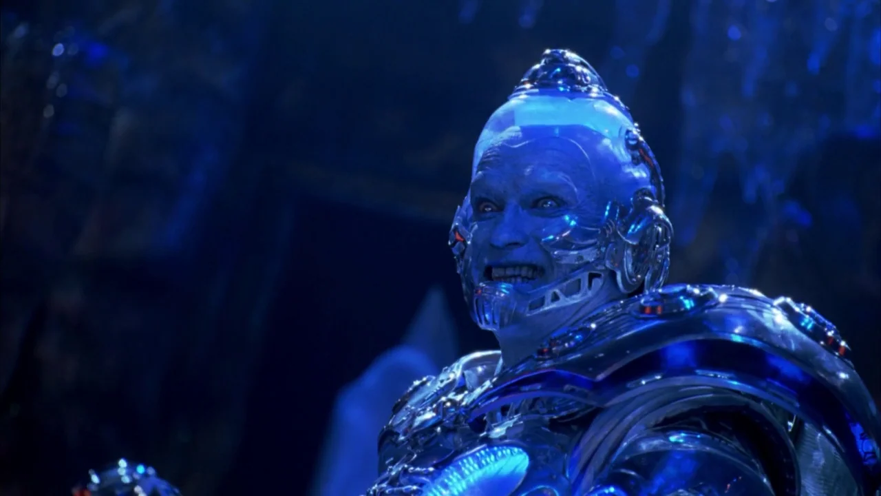 Batman & Robin (1997) movie still: medium — A dark, freezing chamber filled with sharp ice formations and blue light. A man wearing elaborate silver…