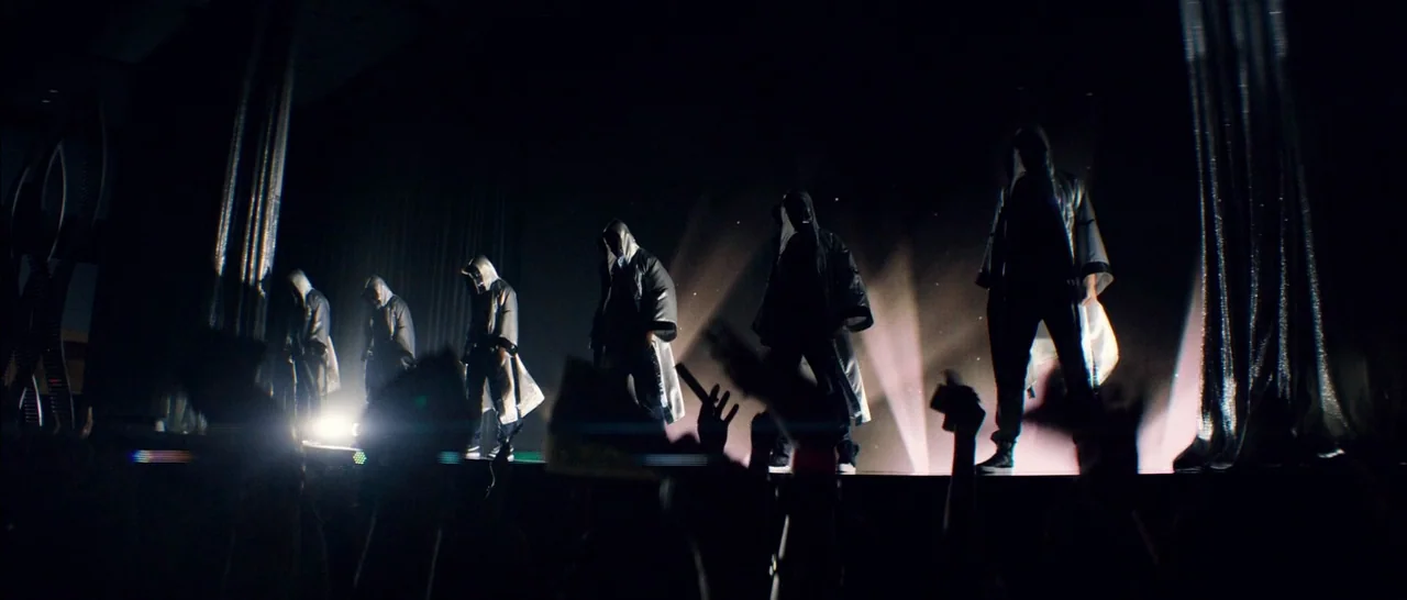 Magic Mike XXL (2015) movie still: wide — Six performers stand on a darkened concert stage under bright rear-facing spotlights. An audience in the…