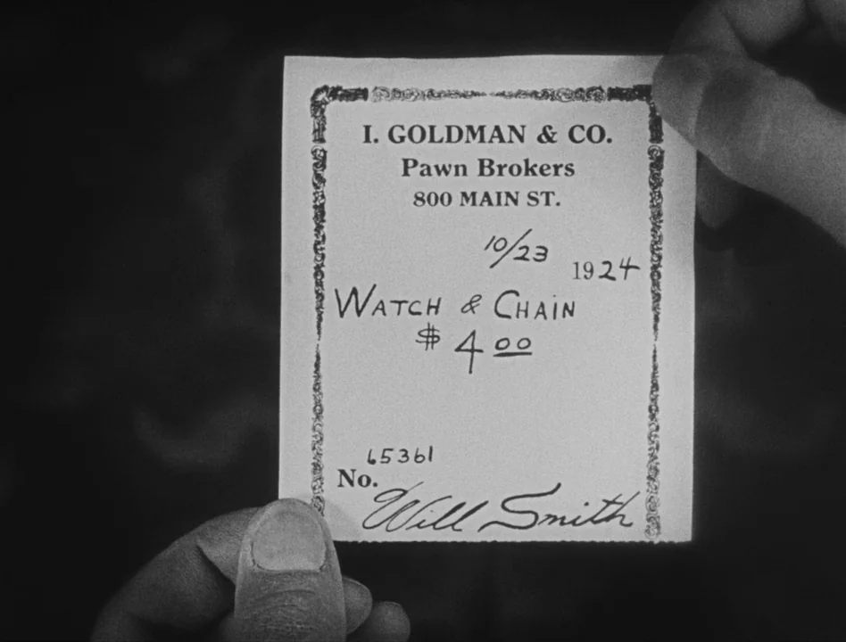 Sherlock Jr. (1924) movie still: closeup — A close-up view of a rectangular paper pawn ticket with decorative printed borders. The ticket contains…